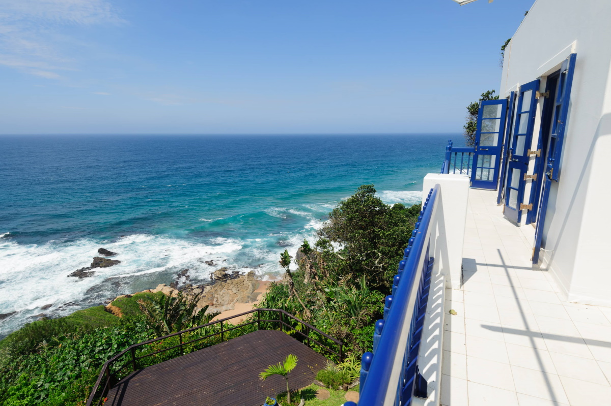 Cliff-top balcony with blue shutters over a rocky cove